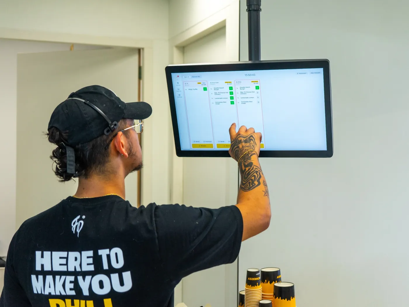 Ein Mitarbeiter von Fat Phill's hakt eine Drive-Thru-Bestellung auf dem Onesix Küchendisplay ab