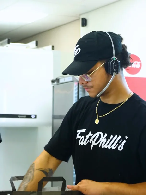 Mitarbeiter von Fat Phill's mit Headset packt eine Drive-Thru-Bestellung ein